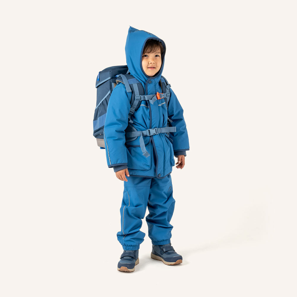 Kind im blauen Outdoor-Look mit Schulranzen vorn
