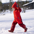 Children's cranberry-colored snow boots on a child, standing sideways in the snow