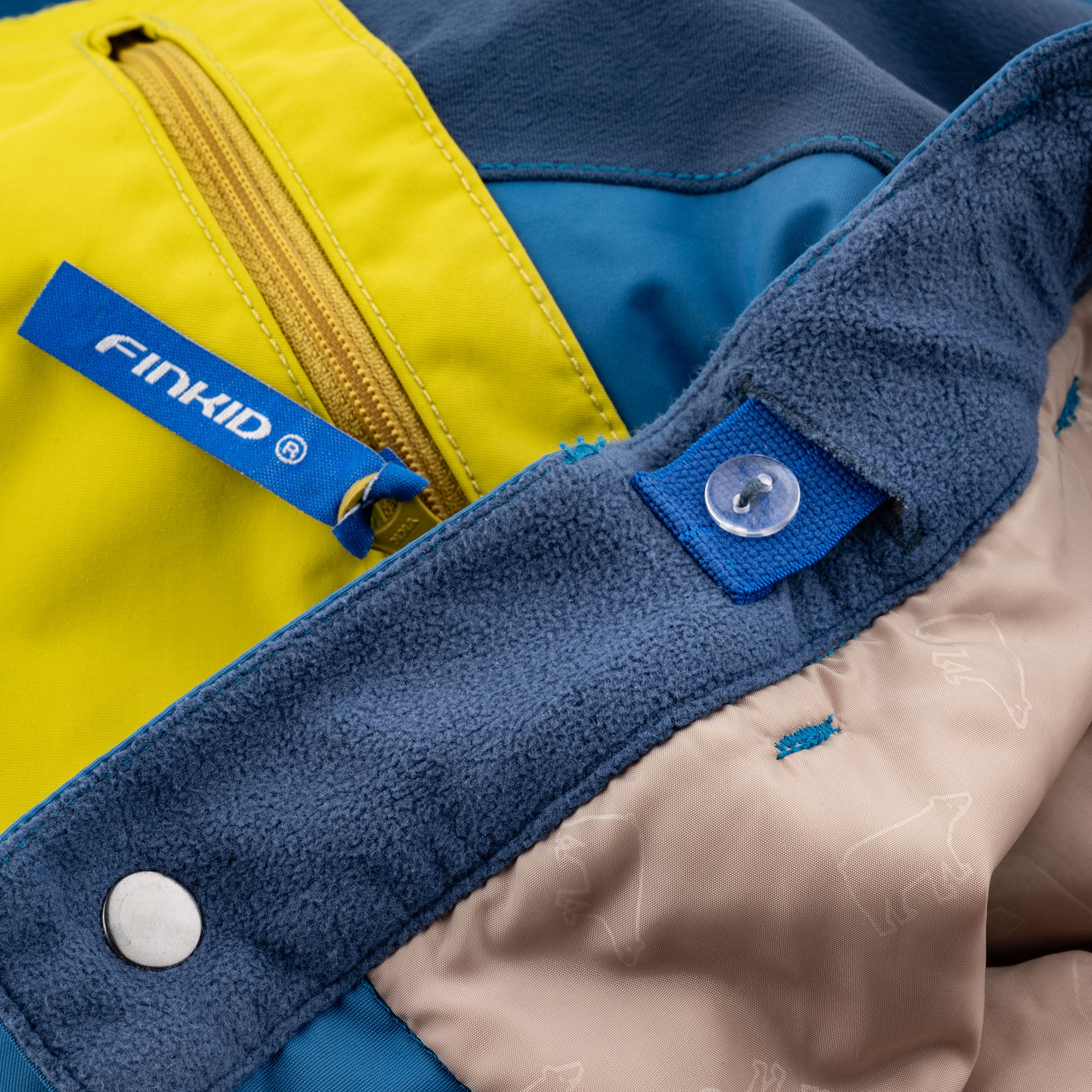 Snow pants with a yellow-blue front panel, fleece cuffs, and snap button
